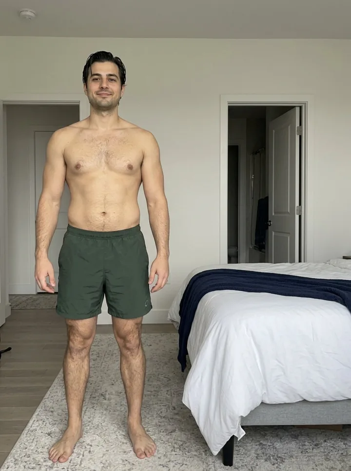 Illustrative sample progress photo, front relaxed pose, plain room